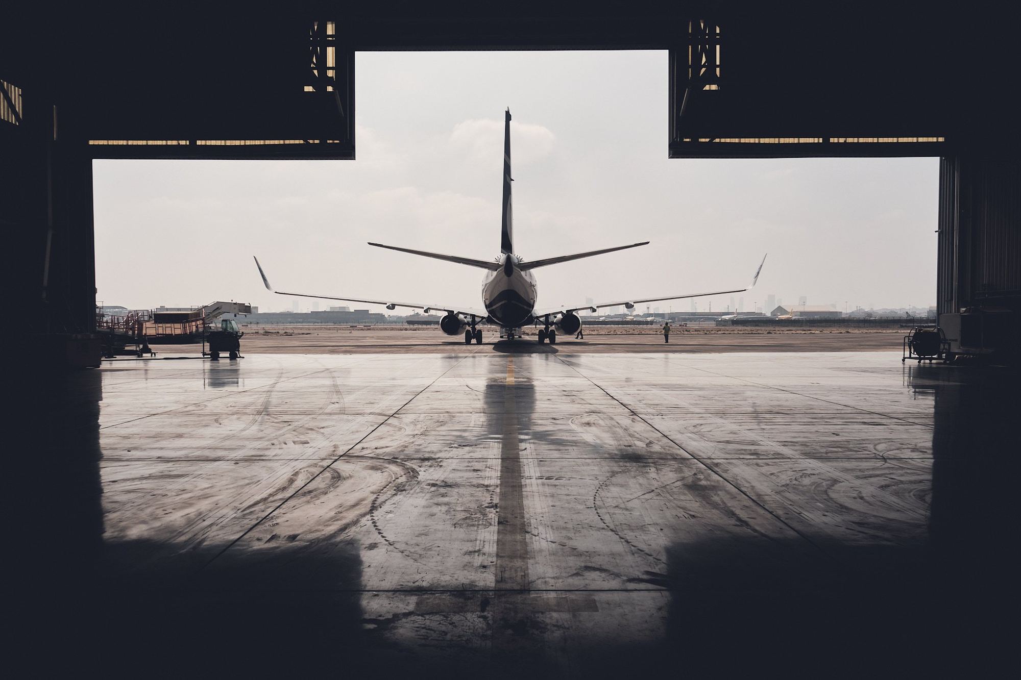 A Texel Air Boeing 737 seen from inside a dark hangar, framed by the open door under an overcast sky.
