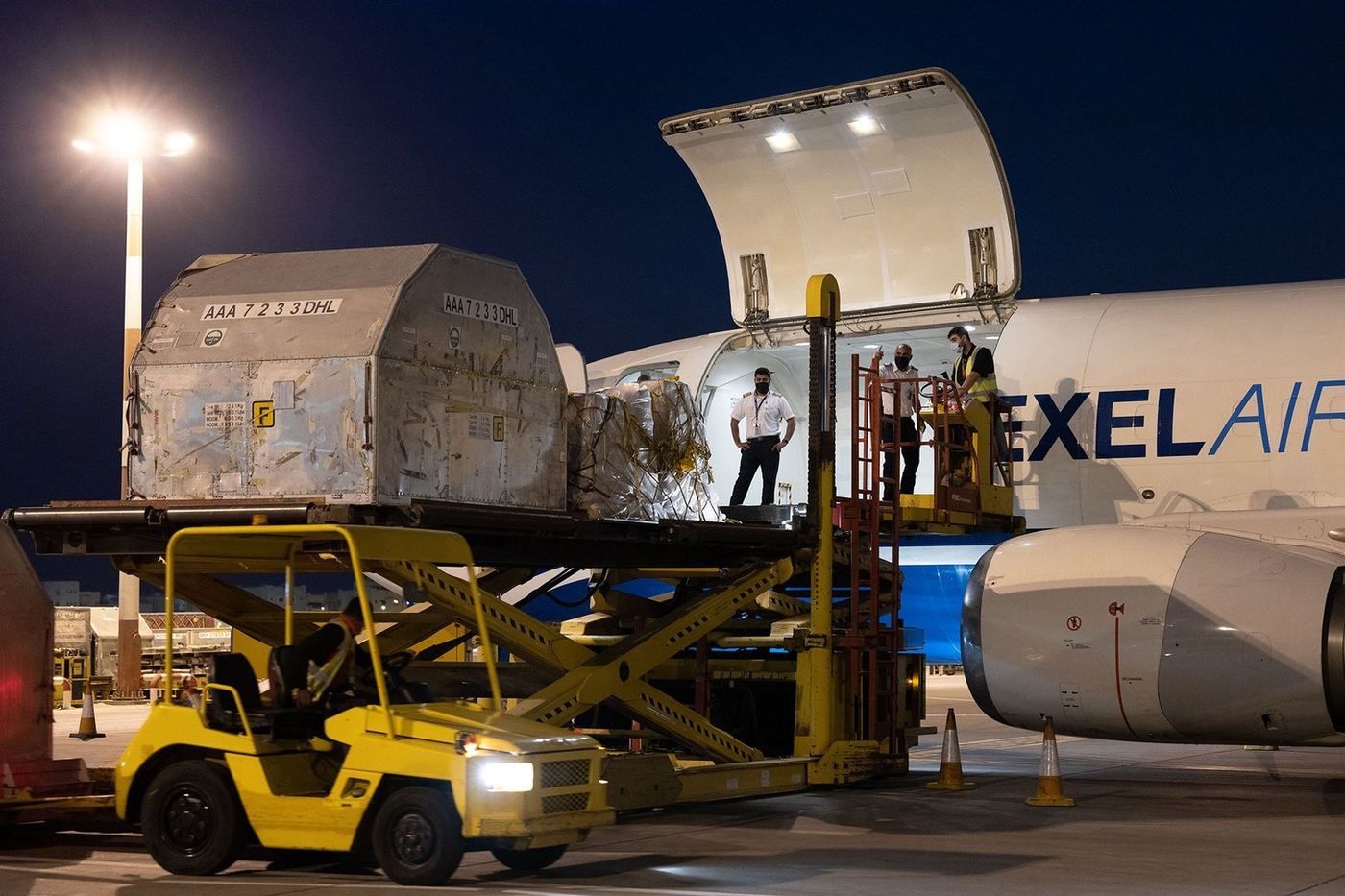 Ground crew loading a pallet into a Texel Air 737 freighter at night.